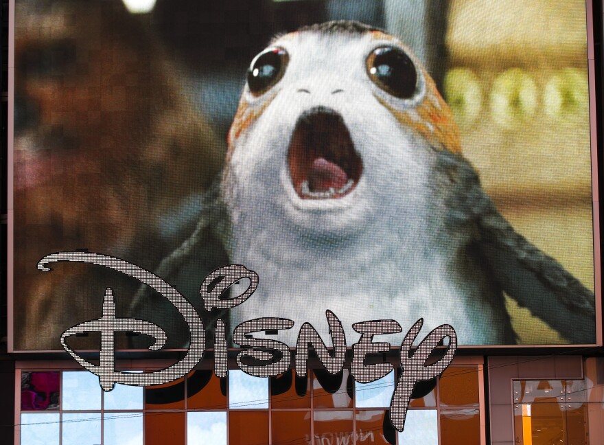 NEW YORK, NY - DECEMBER 14: An advertisement of the new Star Wars film plays on a screen as the Disney logo is displayed outside the Disney Store in Times Square, December 14, 2017 in New York City. The Walt Disney Company announced on Thursday morning that it had reached a deal to purchase most of the assets of 21st Century Fox. The deal has a total value of around $66 billion, with Disney assuming $13.7 billion of Fox's net debt. (Photo by Drew Angerer/Getty Images)