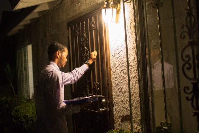 Social worker Alfred McCloud knocks on the front door of a home in south L.A. to check on a toddler. McCloud works the night shift with the Department of Child and Family Services' Emergency Response Team.