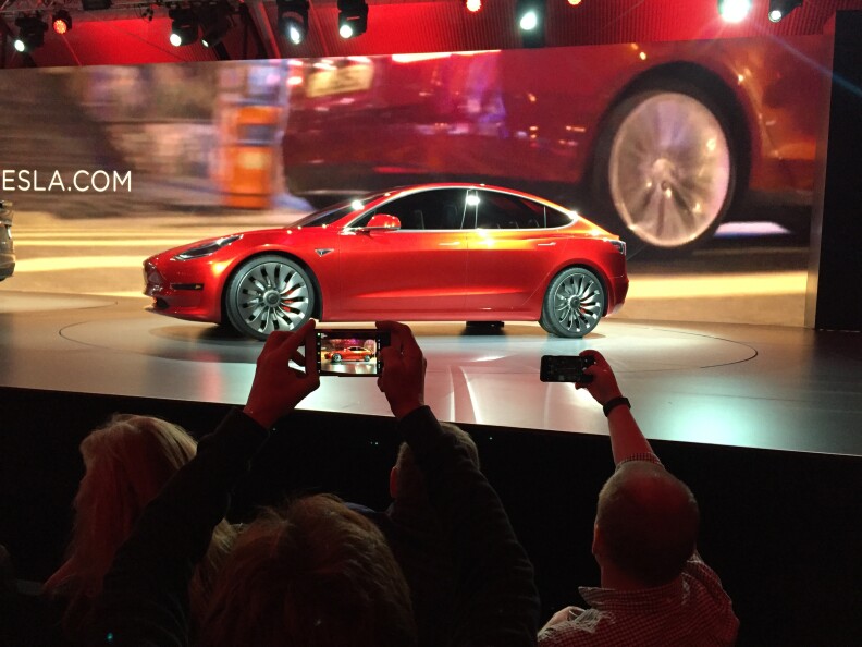 Tesla Motors unveils the new lower-priced Model 3 sedan at the Tesla Motors design studio Thursday, March 31, 2016, in Hawthorne. It doesn't go on sale until late 2017, but in the first 24 hours that order banks were open, Tesla said it had more than 115,000 reservations. Long lines at Tesla stores, reminiscent of the crowds at Apple stores for early models of the iPhone, were reported from Hong Kong to Austin, Texas, to Washington, D.C. Buyers put down a $1,000 deposit to reserve the car. 