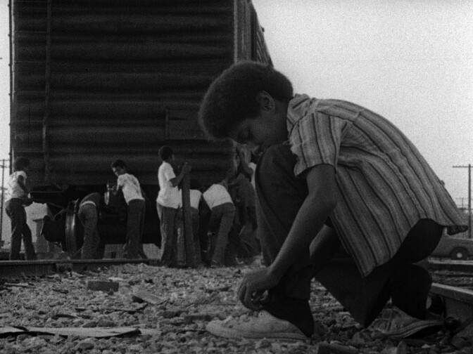 Kids playing by the train in the film KILLER OF SHEEP; a Milestone Film & Video release.