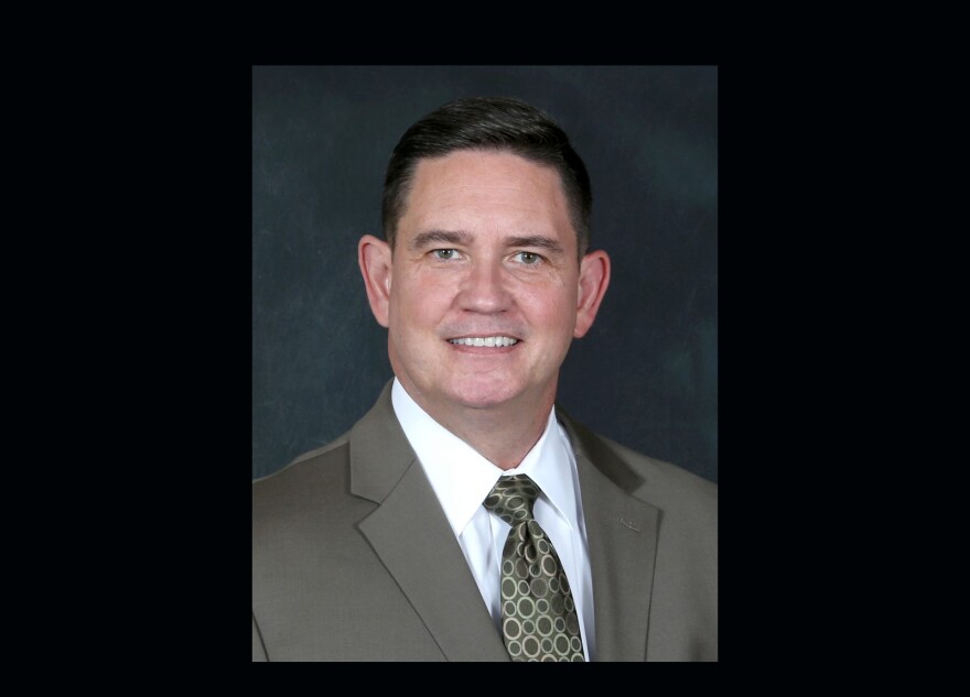 Bobby Cagle is dressed in a olive green suit with a white shirt in this headshot portrait.