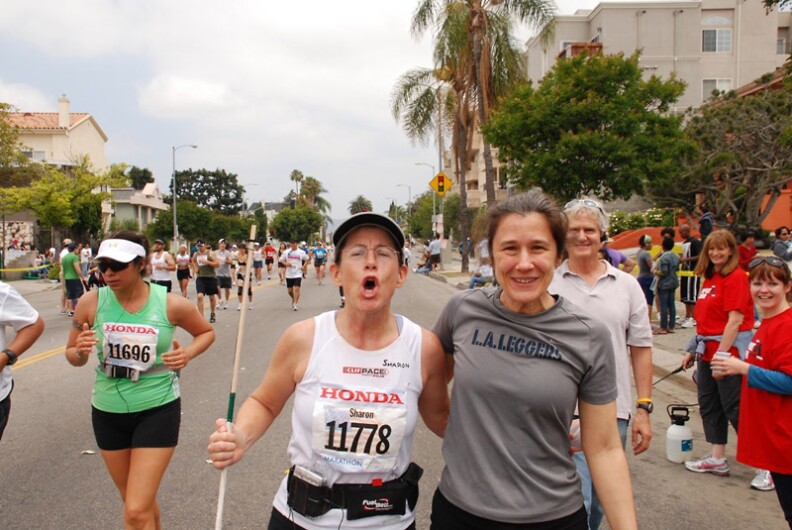 KPCC's Sharon McNary running the 2009 LA Marathon with Judy Hering. Note the dowel in her hand, at the top of which is the tiny microphone ($20 at Radio Shack) she used to record the event.