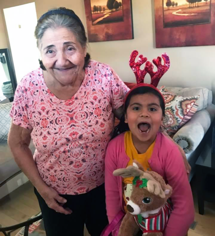 a young girl and an old woman, both wearing pink, stand there and smile