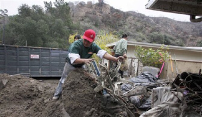 Worker Jose Matios works to clean up mud and debris from Pat Anderson's home in La Canada Flintridge, Calif. on Tuesday, Feb 9, 2010. Some homeowners in mud-ravaged foothill towns north of Los Angeles packed their cars and fled Tuesday as evacuation orders took hold and a new winter storm approached.