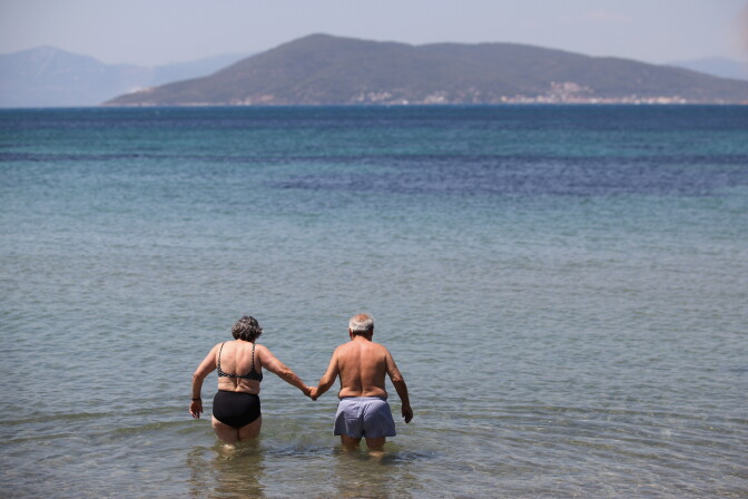 AEGINA, GREECE - JUNE 16:  An elderly couple hold hands as they enter the sea to go for a swim on the island of Aegina on June 16, 2012 in Aegina, Greece. The Greek electorate are due to go to the polls tomorrow in a re-run of the general election after no combination of political parties were able to form a coalition government. Recent opinion polls have placed the anti-bailout party 'Syriza' equal in popularity with the pro-bailout 'New Democracy' in a vote which could determine whether Greece retains the Euro as its currency.  (Photo by Oli Scarff/Getty Images)