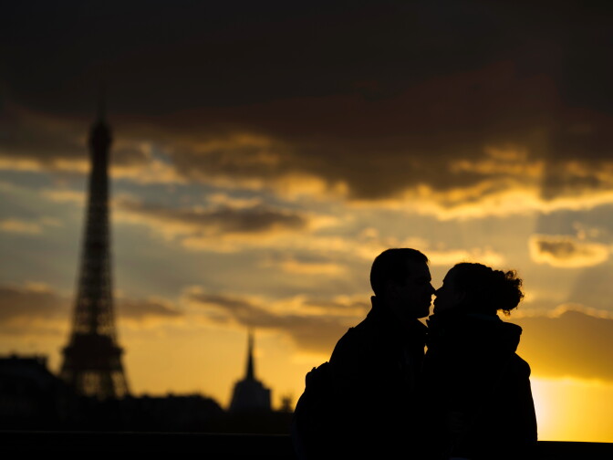 Two people kiss in front of the Eiffel Tower at sunset on March 5, 2014 in Paris.    AFP PHOTO / MARTIN BUREAU / AFP / MARTIN BUREAU        (Photo credit should read MARTIN BUREAU/AFP/Getty Images)