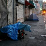 LOS ANGELES, CA - APRIL 19:  A police car stops near homeless people sleeping in their encampments in the early morning hours of downtown sidewalks on April 19, 2006 in Los Angeles, California. Most homeless tents and improvised shelters are taken down at dawn, before their possessions can be hauled away by cleaning crews. A 9th U.S. Circuit Court of Appeals panel ruled last week that a city law making it illegal to sleep or sit on city sidewalks cannot be implemented as long as there is a shortage of homeless shelter beds in Los Angeles. According to a study released in January by the Los Angeles Housing Services Authority, there are nearly 90,000 homeless people live in Los Angeles County but only 9,000 to 10,000 beds available in homeless shelters, single-room occupancy hotels, and other facilities.    (Photo by David McNew/Getty Images)