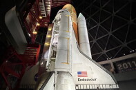 A space shuttle stands in it's launch position. A hatch on the shuttle is open. 
