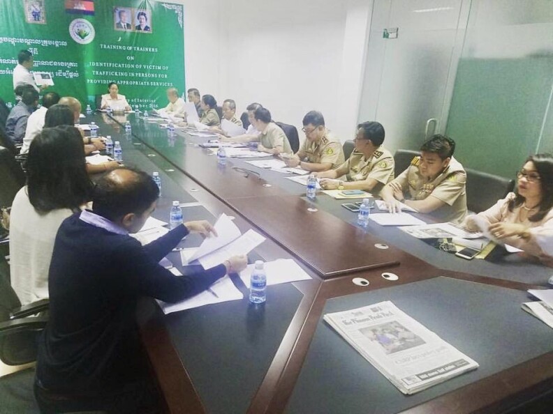 A photo of people sitting at a long table with about dozen on each side. On one side are uniformed officials with the Cambodian government. The other side is made up of people in casual wear.