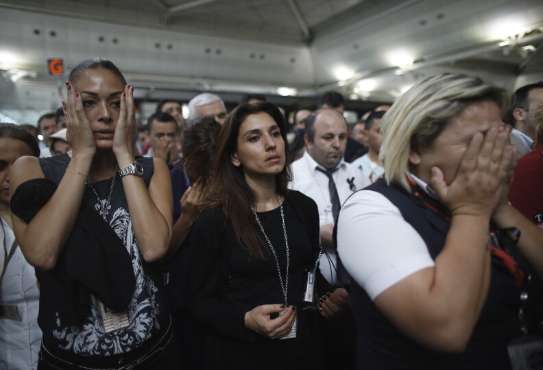People react as family members, colleagues and friends of the victims of Tuesday blasts gather for a memorial ceremony at the Ataturk Airport in Istanbul, Thursday, June 30, 2016. A senior Turkish official on Thursday identified the Istanbul airport attackers as a Russian, Uzbek and Kyrgyz national hours after police carried out sweeping raids across the city looking for Islamic State suspects. Tuesday's gunfire and suicide bombing attack at Ataturk Airport killed dozens and injured over 200. Turkish authorities have banned distribution of images relating to the Ataturk airport attack within Turkey.(AP Photo/Emrah Gurel)