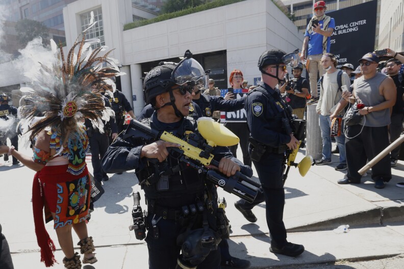 A man in tactical faces a crowd of people. 