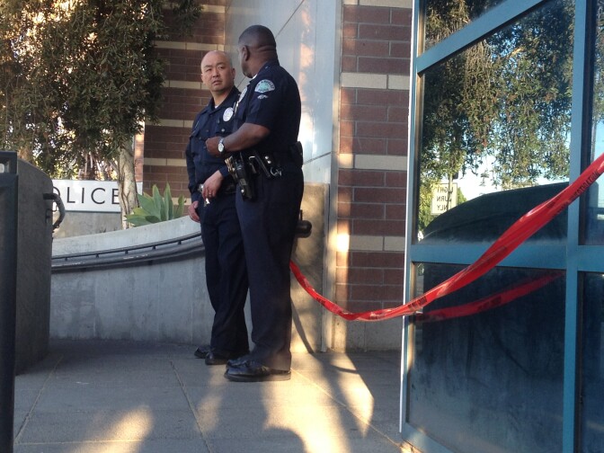 Police officers stand outside the Wilshire station on Tuesday, April 8, 2014. A gunman entered the lobby the night before and opened fire, striking one police officer before he was hit by return fire.