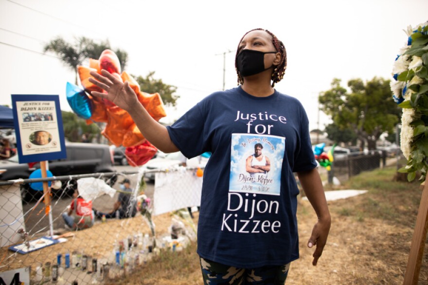 A Black womn wears a t-shirt that reads: Justice for Dijon Kizzee