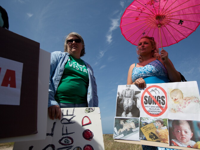 Chrystal Coleman hides from the sun under a parasol and talks with other anti-nuclear protesters at San Onofre State Beach near the inactive nuclear plant on April 6, 2012.