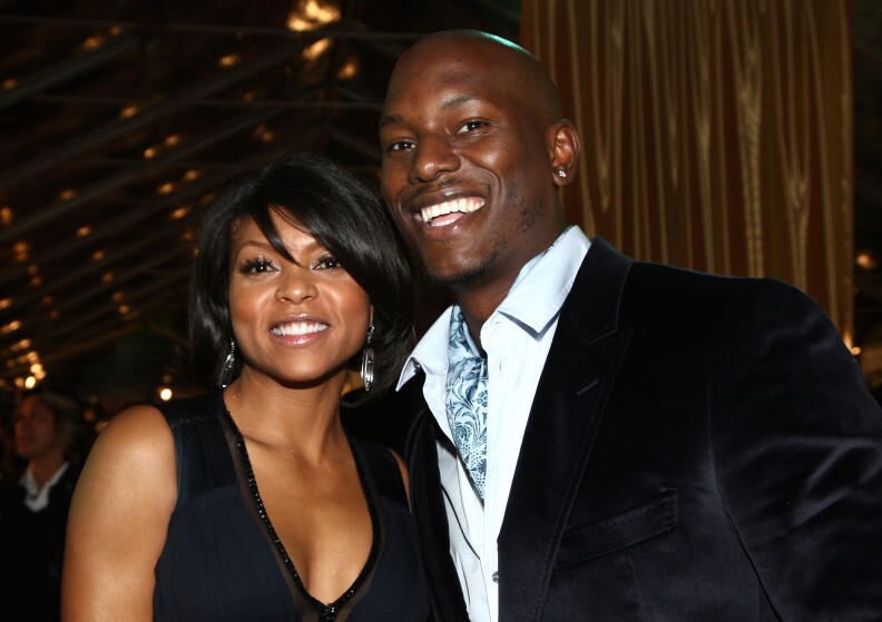 A Black woman and Black man pose together for a picture at a movie premiere, smiling for the camera.