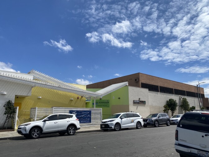 A building is show across the street, a sign on the side of it reads "Central recreation center." Cars line both side of the paved street.