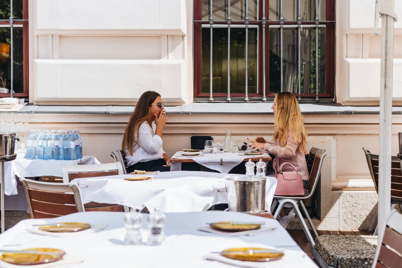 Two women sit at a table for outside dining.