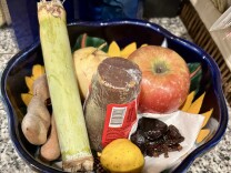 An apple, prunes, a guava and other items in a ceramic bowl.