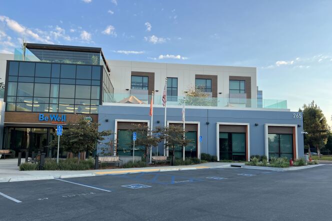 A two story building has a glass entry. Be Well is over the doorway.