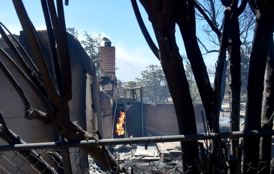 A fire continues burning amid the rubble of a demolished home in the community of Squirrel Valley in Lake Isabella, California on June 24, 2016.