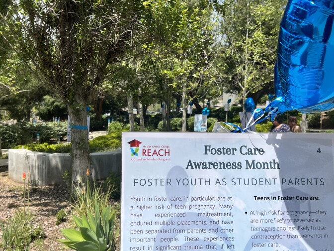 A Foster Care Awareness Month laminated poster standing in the garden with a blue heart balloon.