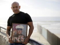 U.S. Marine Corps veteran Antonio Romo on Feb. 13, 2017, holds a picture of himself taken from his days at boot camp, as he poses for a portrait next to the U.S. border wall on the beach in Tijuana, Mexico. Romo is part of a group of dozens of U.S. military veterans who were deported after criminal convictions and for years have fought to be allowed to return.