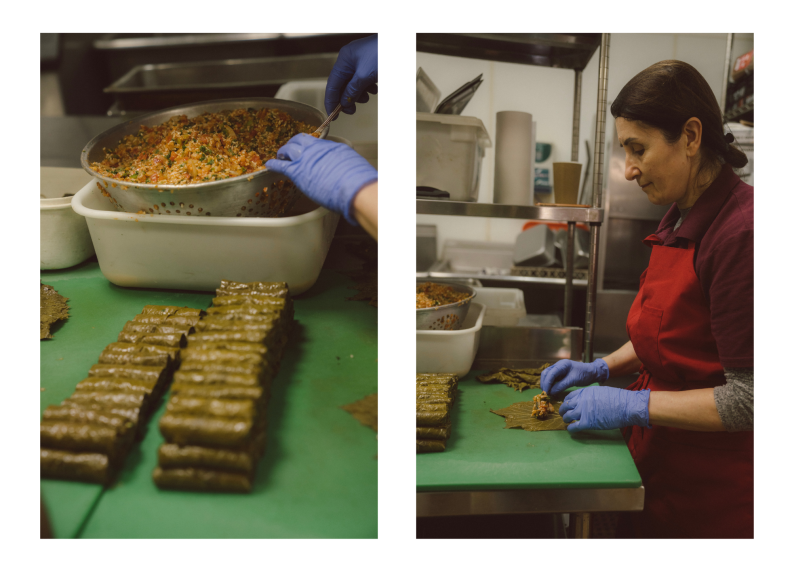 A diptych: On the left, a vertical image of stacked rows of stuffed grape leaves. Towards the back of the image there's a big metal bowl full of green, red, and beige filling. Two hands wearing blue surgical gloves tick out from the right of frame and spoon filling. On the right, a vertical image of an older Armenian woman wearing a dark red sweater and red apron. She stands at a metal table with a large green cutting board. There's a spread out grape leaf with a dollop of filling she's starting to roll.