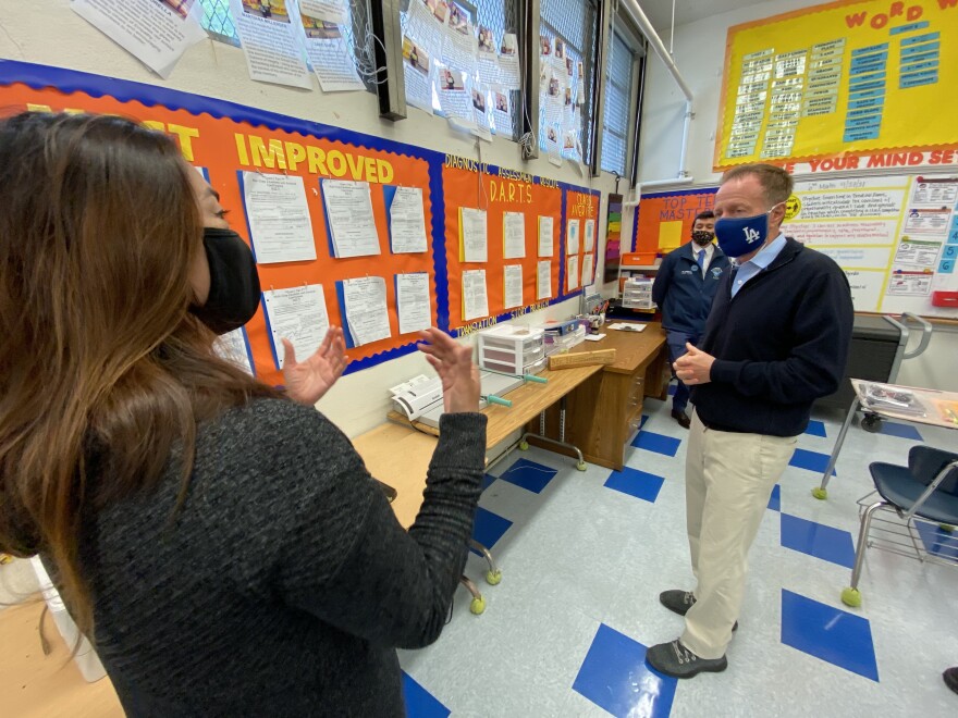 Then-L.A. Unified School District Superintendent Austin Beutner tours a middle school wearing a mask with "LA" on it. He's talking to a teacher.