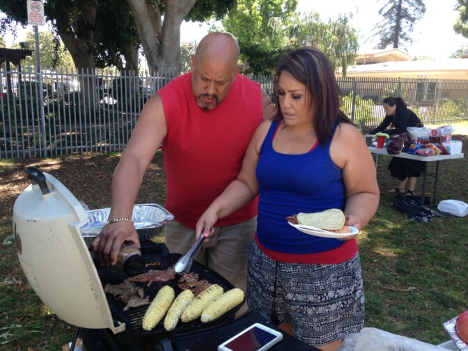 Javier Velasquez and his wife add spices to the carne asada on the grill. The family has been celebrating July 4 at South Gate Park for 13 years.