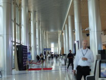 A wide view across the large terminal that looks down a row of tall white multiple columns. People are walking in the frame. The ceiling is high up.