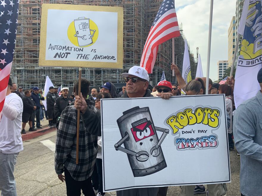 A port worker holds up signs that protest automation in place of humans.