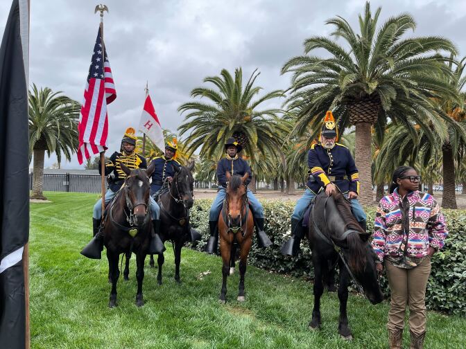 A quartet of four Black men in uniform look at the camera. All of them are on horseback.