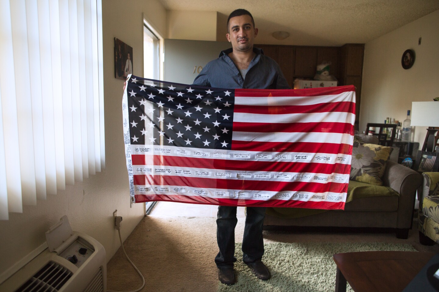 Tariq Abu Khumra, a former translator for U.S. forces in Iraq,  holds an American flag, which was given to him by American troops, in his Glendale apartment.