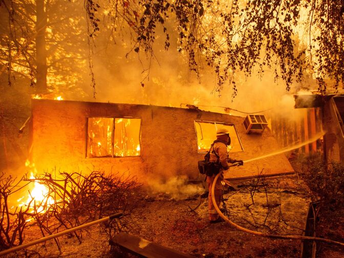 Firefighters battle flames at a burning apartment complex in Paradise, California in November. State fire officials say power lines coming into contact with trees have sparked multiple Northern California wildfires in recent years. PG&E submitted its "wildfire mitigation plan" Wednesday, which lets it cut off power to any of its 5.4 million customers during extremely dry and windy weather.