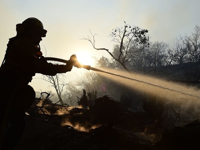 LAFD Firefighter Allen Janzen puts down smoldering embers in the Bel Air neighborhood of Los Angeles while fighting the Skirball Fire on December 6, 2017.
