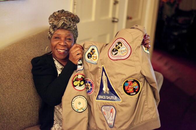 Janice holds up her 'Members Only' jacket which has patches from every NASA shuttle mission. 