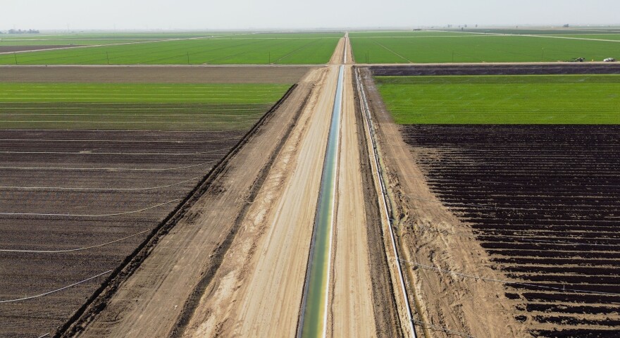 This aerial view shows an irrigation canal through agriculture fields.