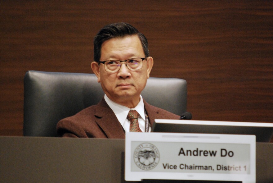 A man in a suit jacket and tie looks off to the side. His nameplate is in the foreground: "Andrew Do, Vice Chairman, District 1."