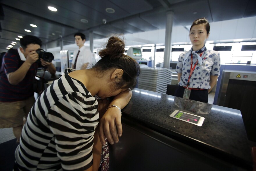 An unidentified family member of one of two Chinese students killed in a crash of Asiana Airlines' plane on Saturday, cries at the Airlines' counter as she and other family members check in a flight to San Francisco at Pudong International Airport in Shanghai, China, Monday, July 8, 2013. The Asiana flight crashed upon landing Saturday, July 6, at San Francisco International Airport, and the two of the 307 passengers aboard were killed. (AP Photo/Eugene Hoshiko)
