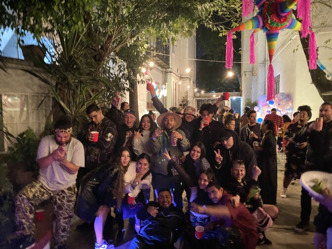 A group of over a dozen people pose for a photo at a backyard party with a piñata. 