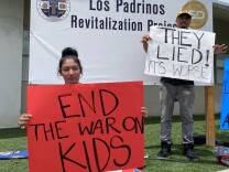 A protester holds a sign that reads 'End the War on Kids' 