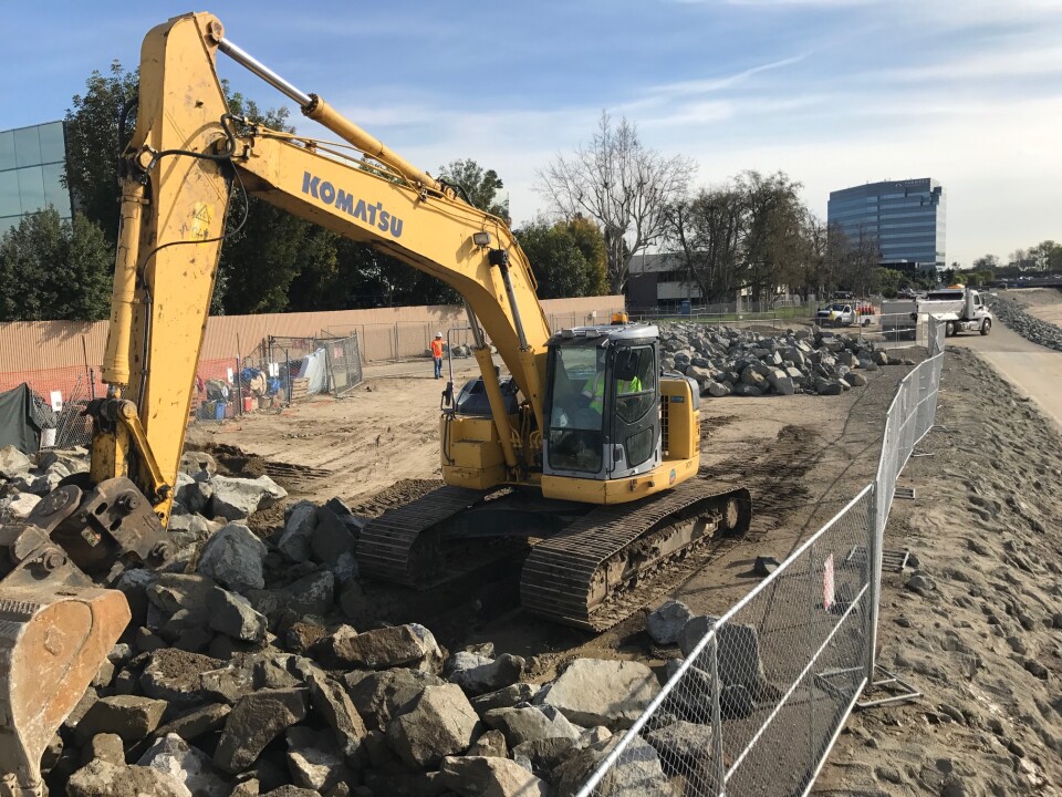 An earthmover pushes boulders to cover an area previously occupied by several homeless people.