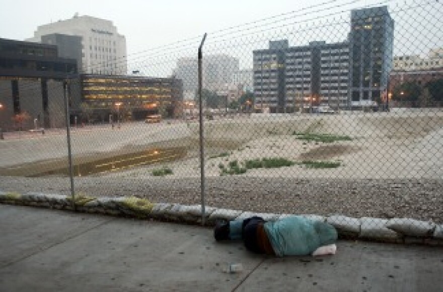 A homeless man sleeps on the sidewalk next to a prepared downtown lot where the new Los Angeles United States Courthouse was supposed to be built.