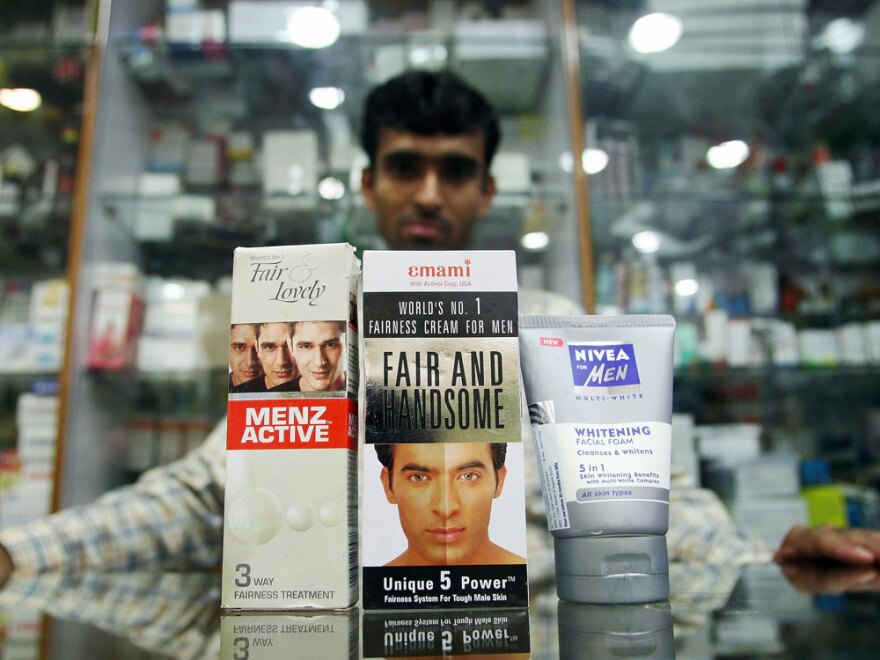 An Indian salesman poses with men's skin fairness products at a shop in New Delhi.