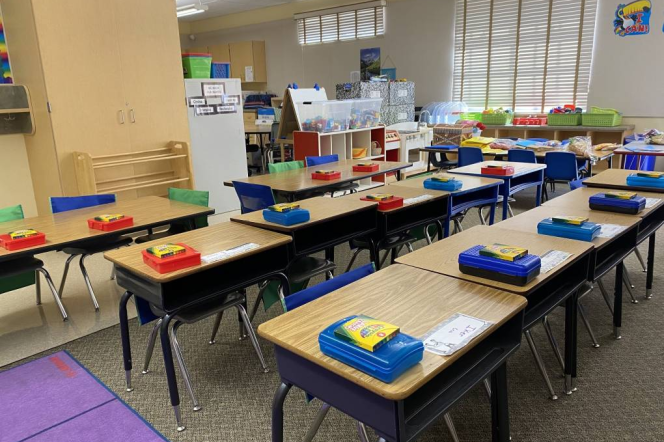 A children's classroom with pencil boxes and desks lined up in rows