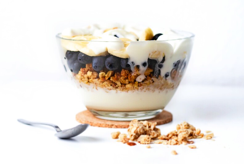 a bowl of plain yogurt layered with banana slices, blueberries and granola
