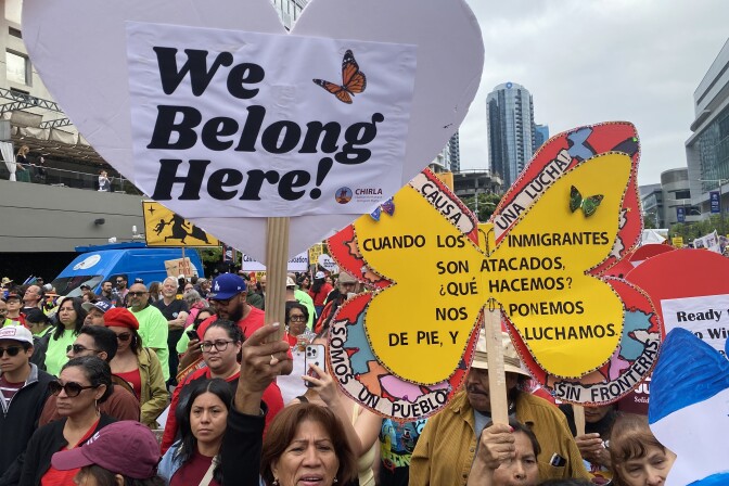 A crowd of people carrying colorful signs in downtown Los Angeles.