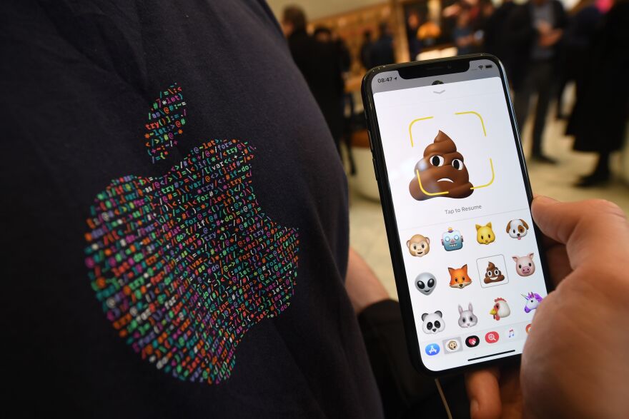 A member of Apple staff pose with a new Apple iPhone X smartphone showing new emoji features in Apple's Regent Street store in central London on November 3, 2017 after it opened for the first sales of the new smartphone.
Apple's flagship iPhone X hit stores on November 3, as the world's most valuable company predicted bumper sales despite the handset's eye-watering price tag and celebrated a surge in profits. The device features facial recognition, cordless charging and an edge-to-edge screen made of organic light-emitting diodes used in high-end televisions. It marks the 10th anniversary of the first iPhone release and is released in about 50 markets around the world.
 / AFP PHOTO / Chris J Ratcliffe        (Photo credit should read CHRIS J RATCLIFFE/AFP/Getty Images)