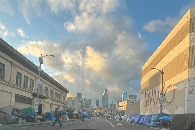 Makeshift tents line with both sides of a city street with tall skyscrapers visible in the background.