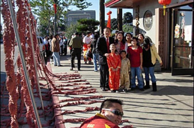 A family poses before firecrackers (L) are set off in front of Chinatown's Teo-Chew Association.